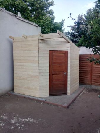 Frissen épített kerti tároló, amely fontos helyet biztosít a kerti szerszámoknak és bútoroknak, megőrizve a kert rendezett megjelenését.